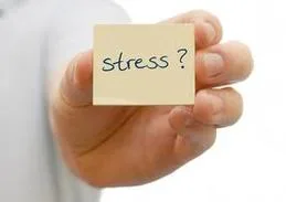 Une main tend un post-it beige sur lequel est écrit à la main « stress ? ».