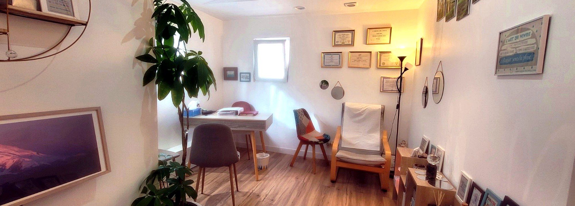 Le cabinet : une pièce claire au parquet, un bureau et deux chaises, un fauteuil à bascule, une grande plante verte et des diplômes encadrés.